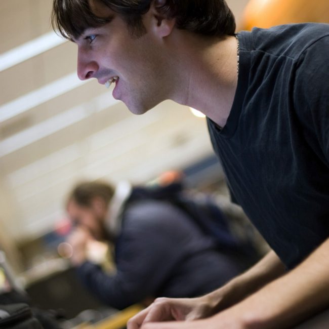 A young man or student using a personal computer happily.